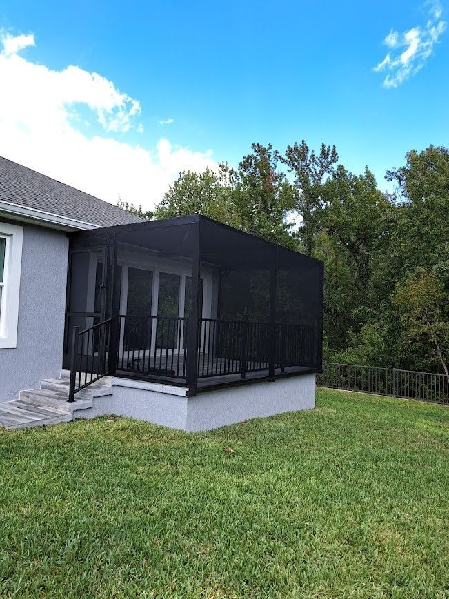 A screened in porch is sitting in the backyard of a house.