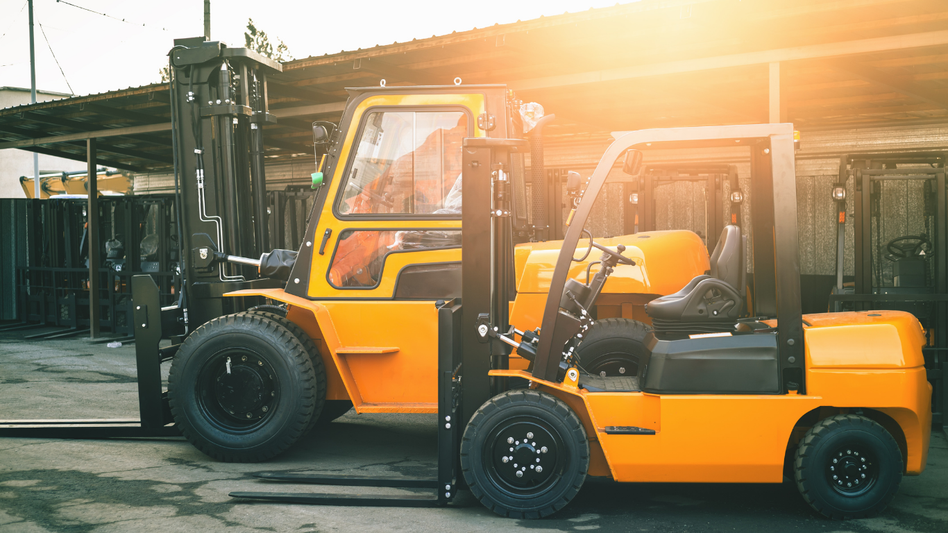 Two yellow forklifts parked outside a warehouse.