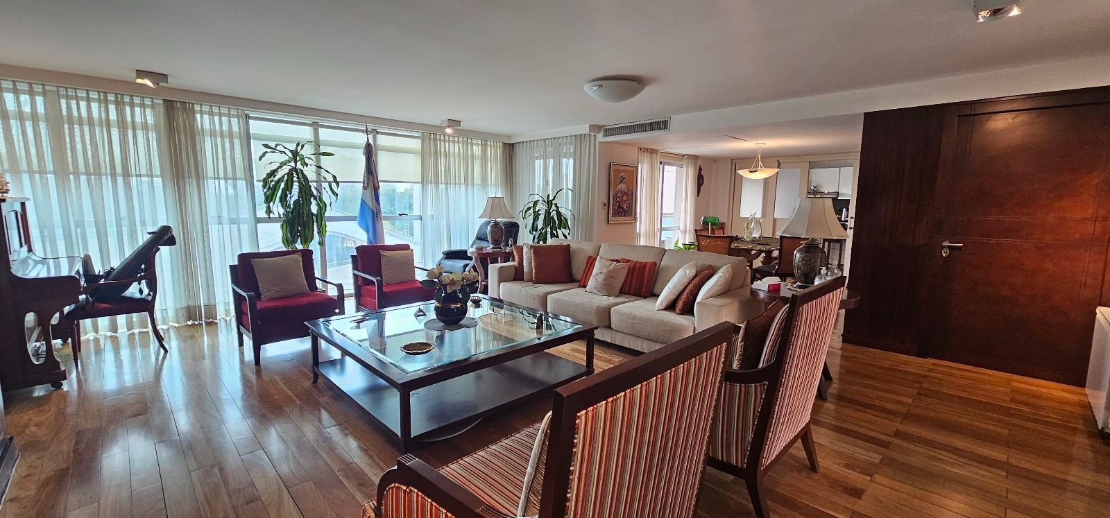 Balcón con mesa y sillas de exterior junto a un pasillo, con vistas a los edificios de apartamentos de la ciudad.