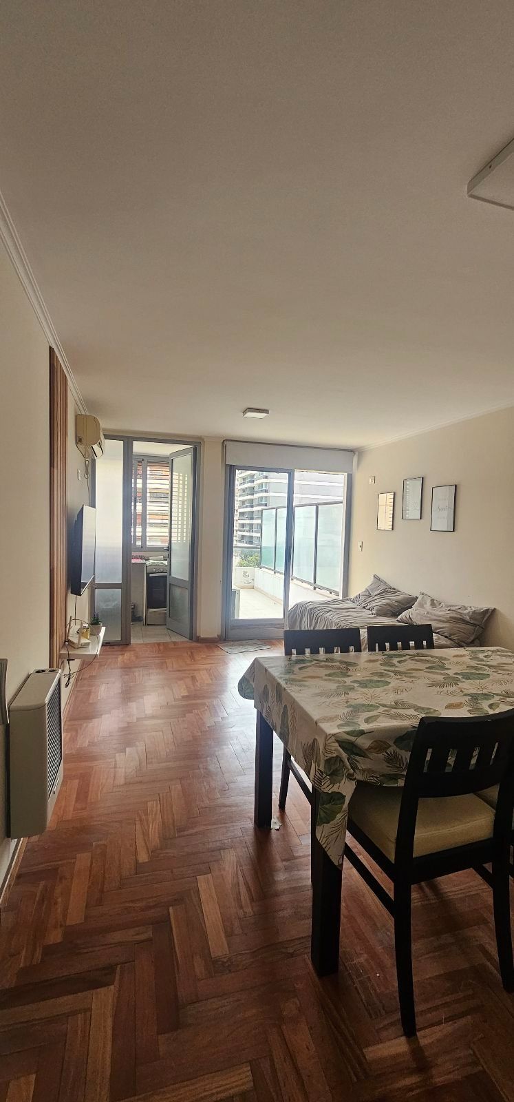 Comedor luminoso en apartamento con suelo de madera, mesa, sillas y puertas que dan al balcón.