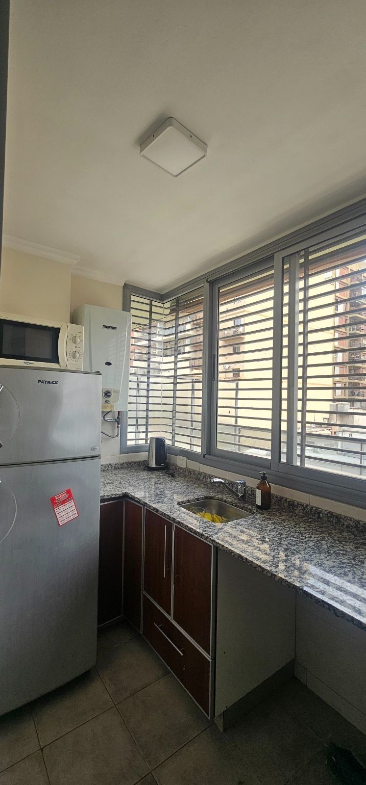 Comedor luminoso en apartamento con suelo de madera, mesa, sillas y puertas que dan al balcón.