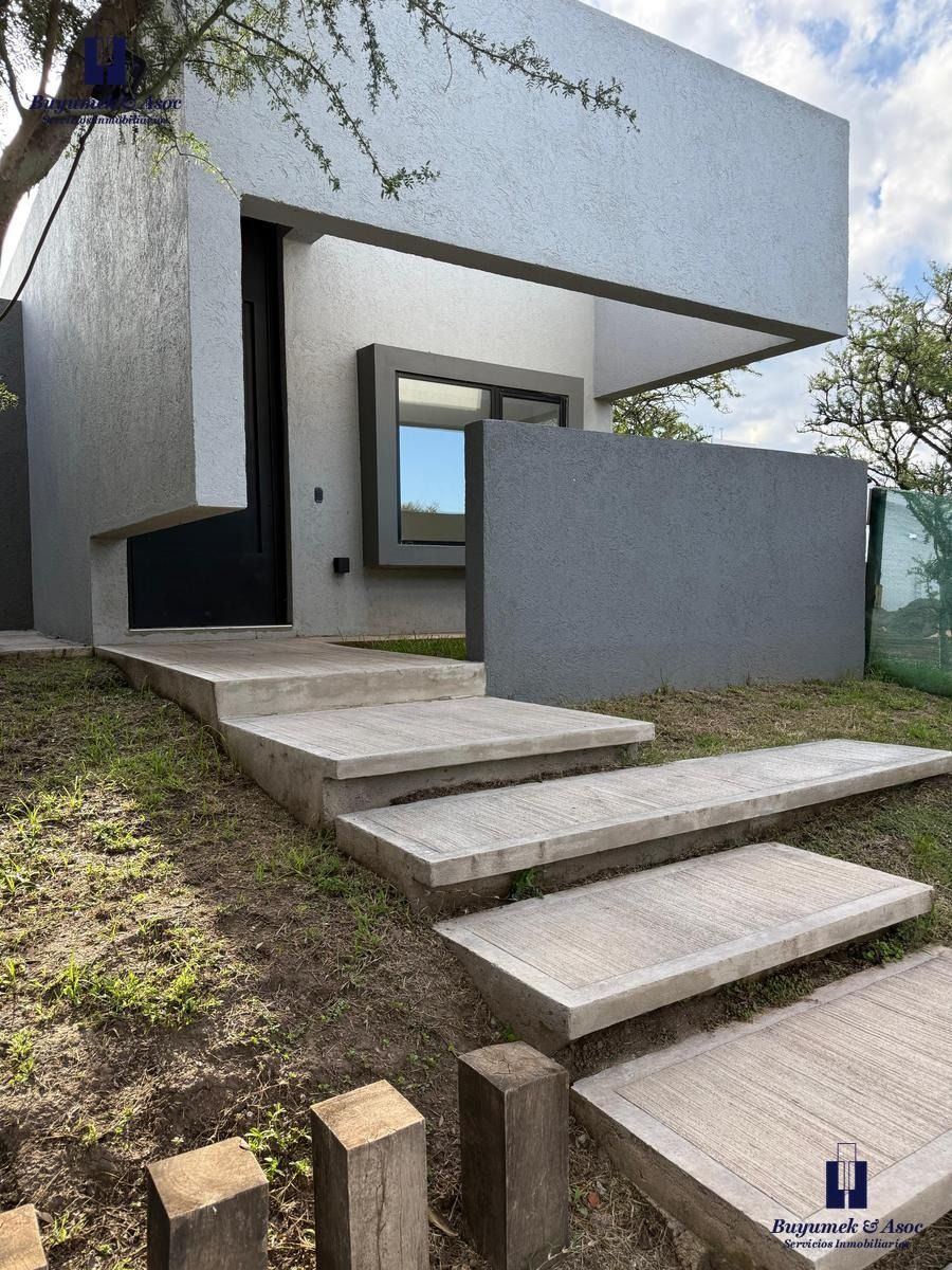 Casa moderna de color gris con un camino escalonado de hormigón que conduce a la entrada bajo un nivel superior en voladizo.