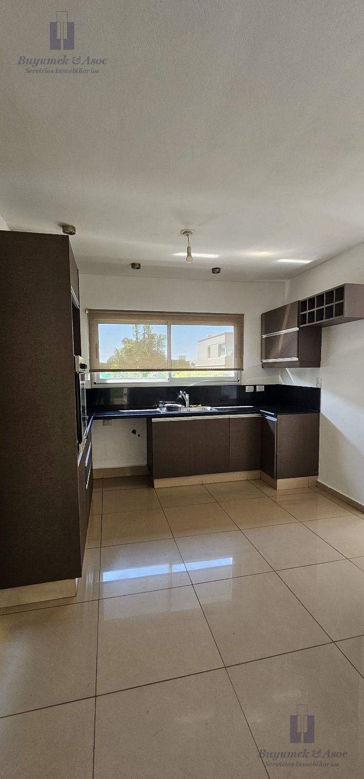 Comedor y cocina amplios y luminosos con puertas de cristal, mesa de madera y vistas a una piscina exterior.