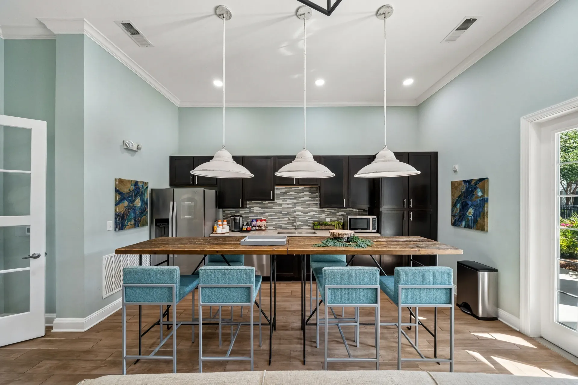 Community kitchen with a large wooden island and bar stools, stainless steel appliances, and dark cabinets at Atlantic on the Avenue in North Charleston, SC.
