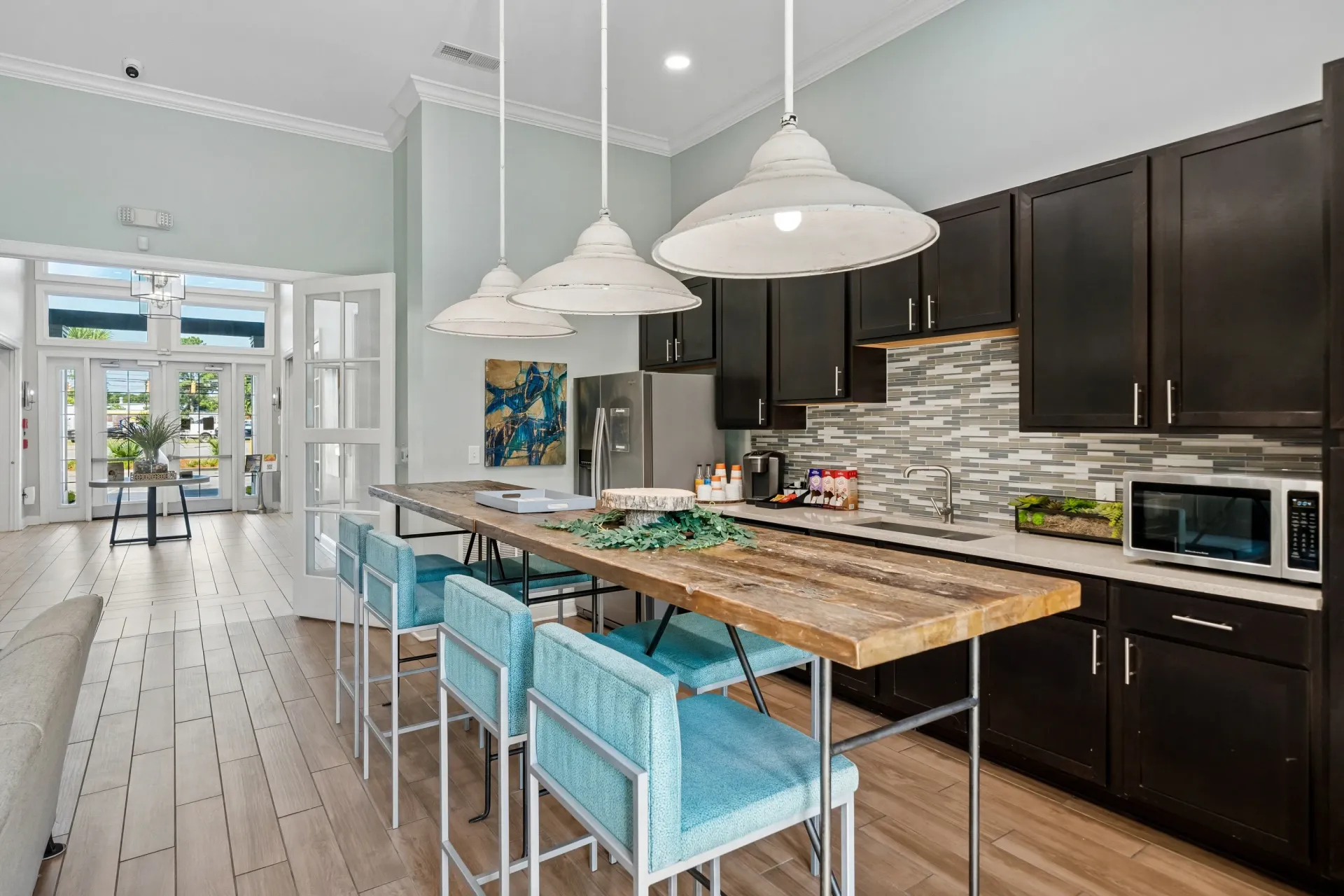 Community kitchen with a long island and blue bar stools at Atlantic on the Avenue in North Charleston, SC.