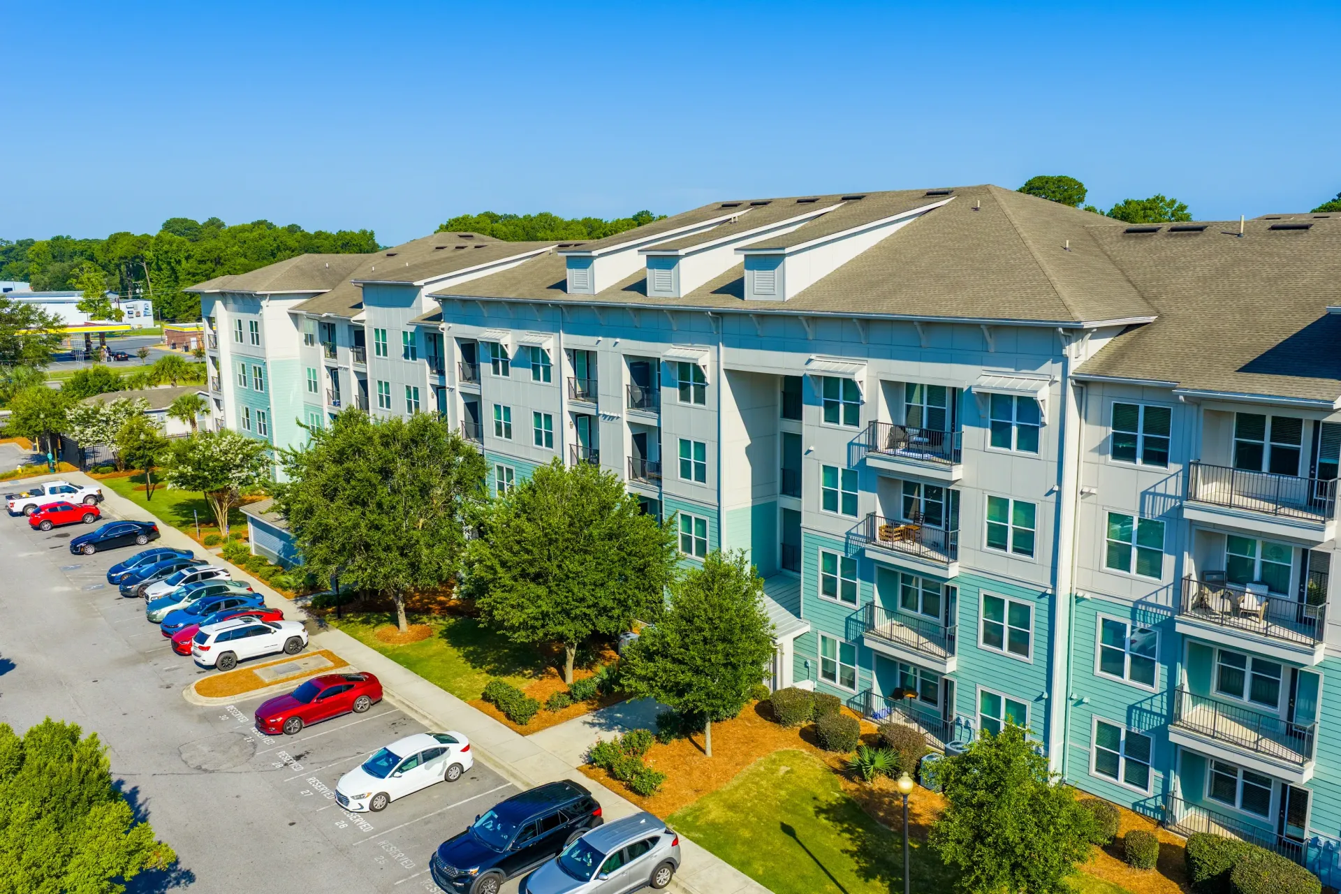 Exterior view of a modern apartment building with balconies and a parking lot at Atlantic on the Avenue in North Charleston, SC.