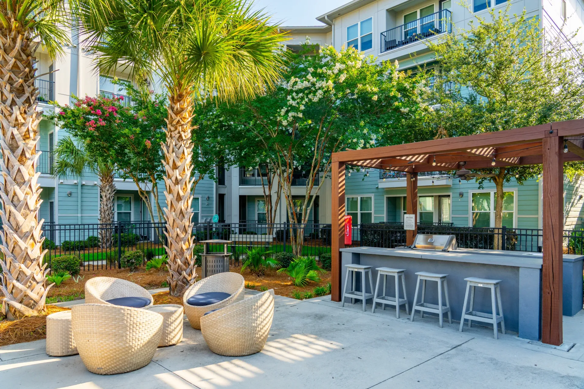 Outdoor seating area with bar and grill under a wooden pergola at Atlantic on the Avenue in North Charleston, SC.