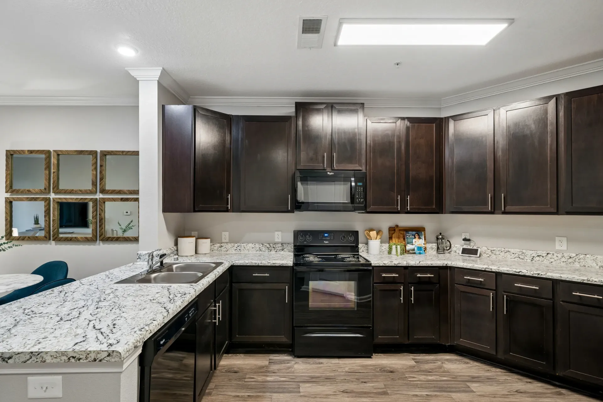 Modern kitchen with dark wood cabinets, granite countertops, and stainless steel appliances.