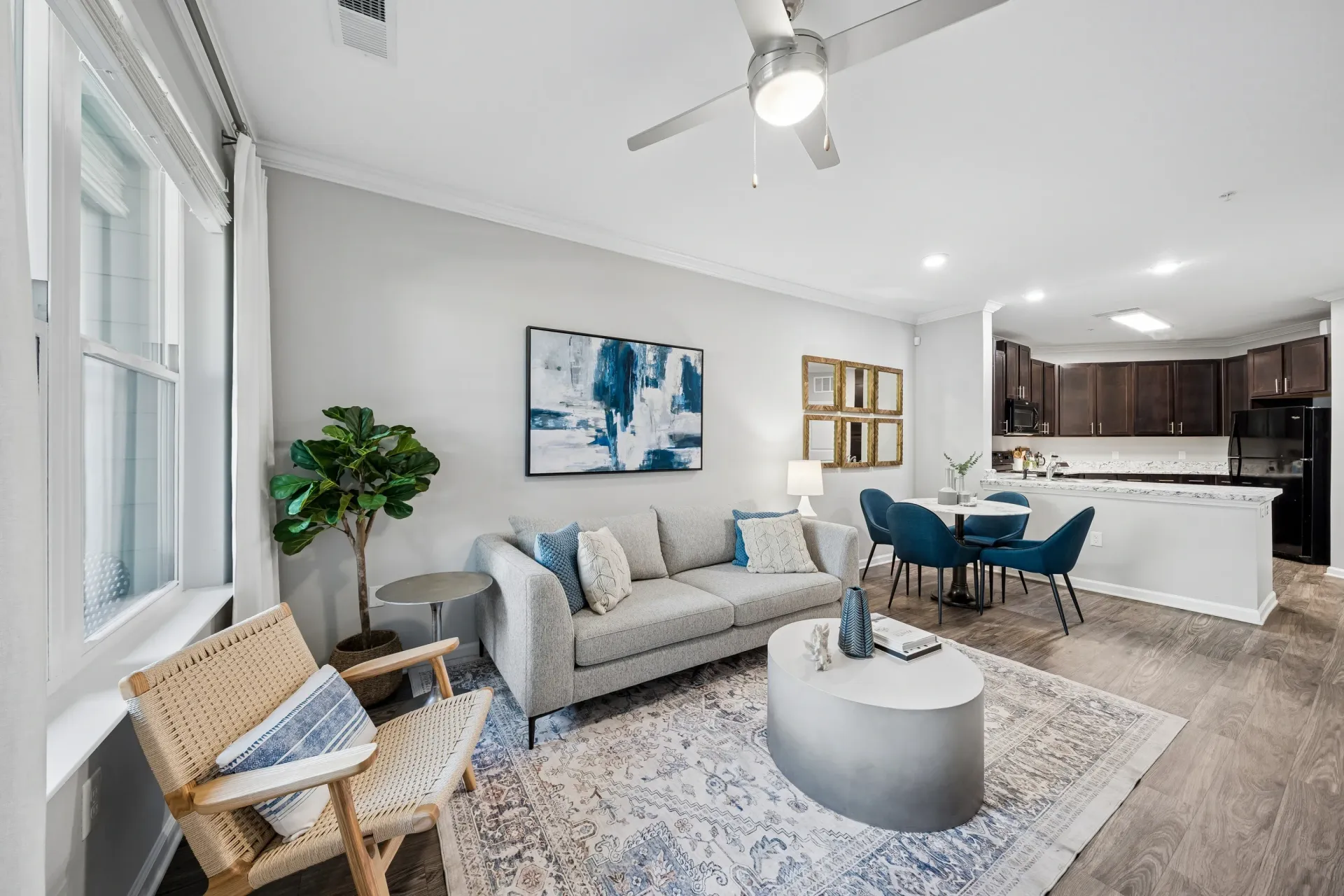 Stylish living room with gray sofa, accent chair, coffee table, and open-concept kitchen area at Atlantic on the Avenue in North Charleston, SC.