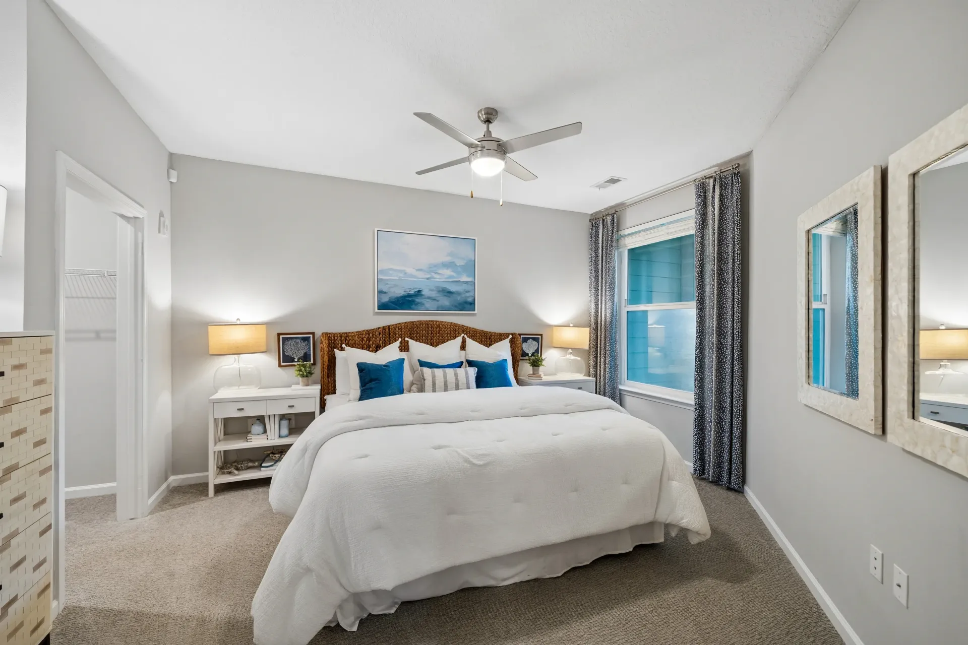 Queen-size bed with white linens and blue accent pillows in a bedroom at Atlantic on the Avenue in North Charleston, SC.