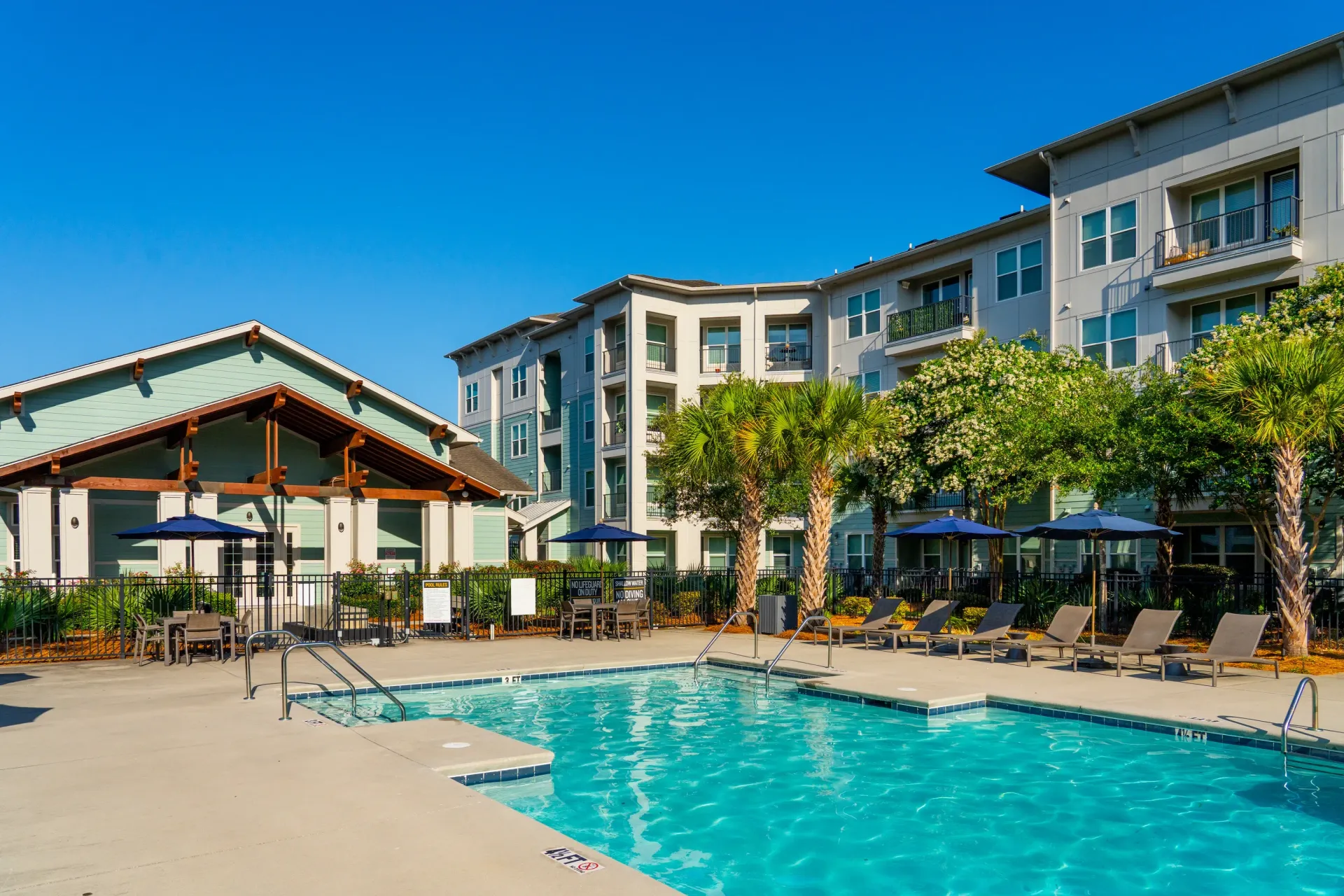 Resort-style swimming pool and lounge chairs with apartment buildings in the background at Atlantic on the Avenue in North Charleston, SC.