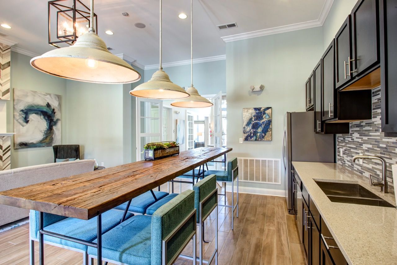 Bright kitchen with a long rustic wood island, blue bar stools, and dark cabinets at Atlantic on the Avenue in North Charleston, SC.
