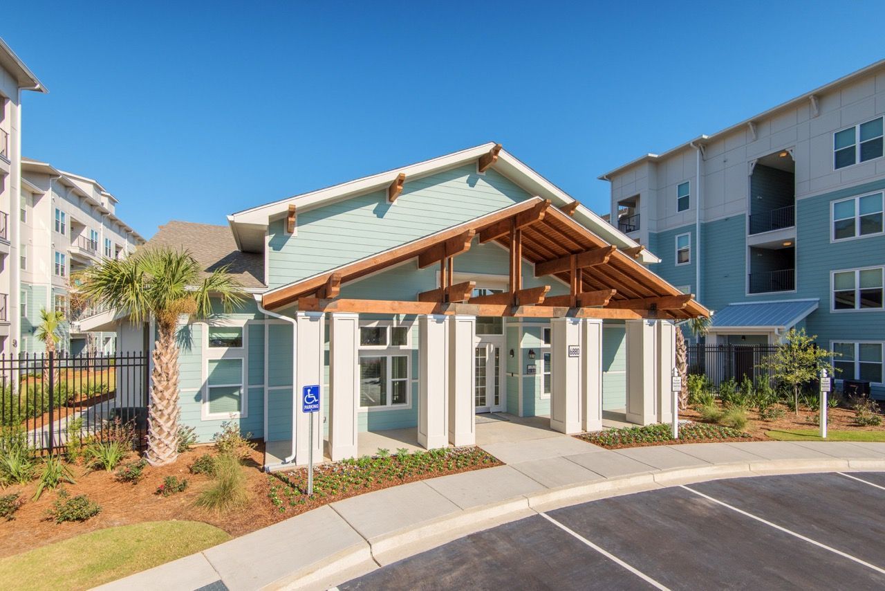Exterior entrance to a modern apartment community with a covered entry and handicap parking sign at Atlantic on the Avenue in North Charleston, SC.