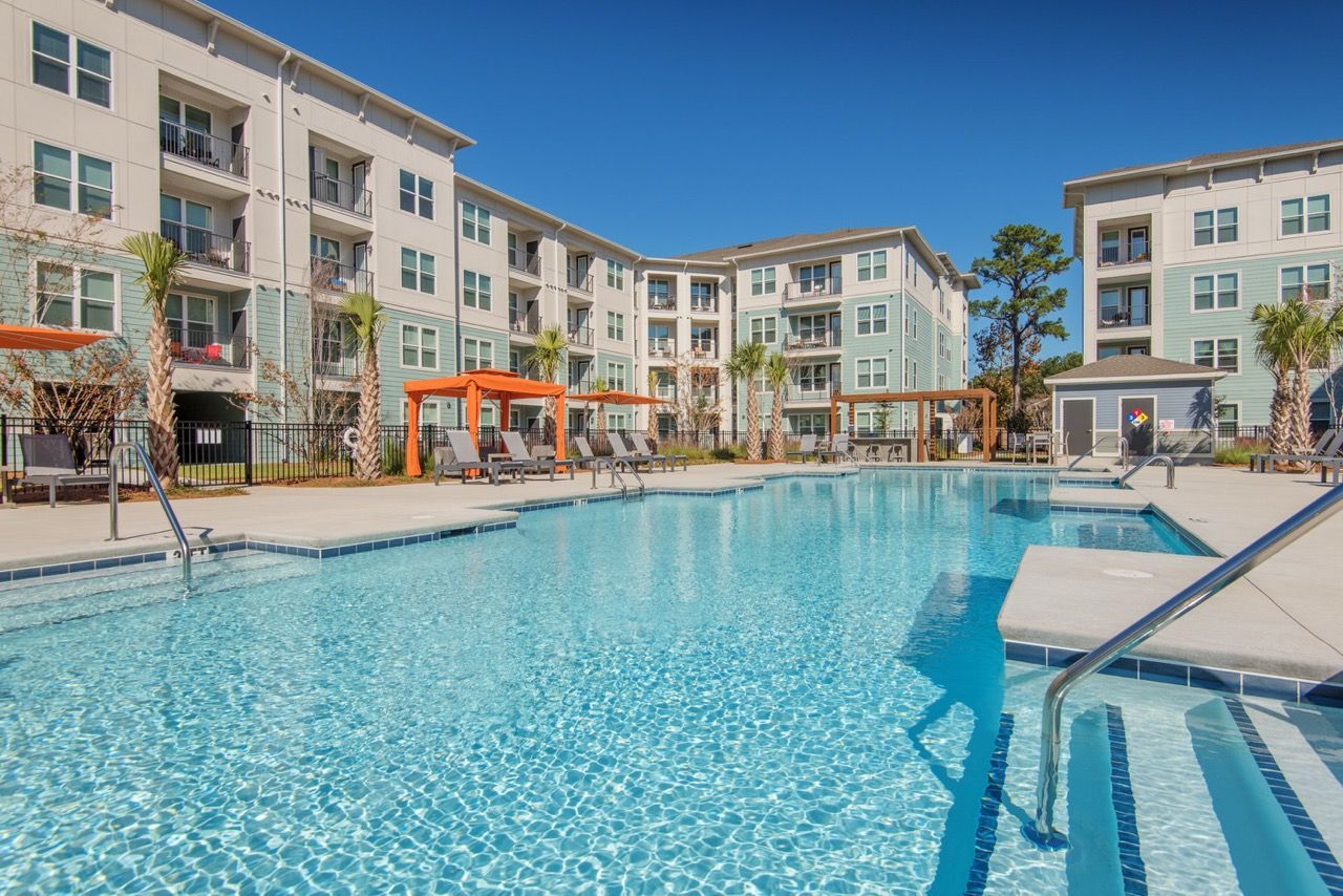 Outdoor apartment community pool with lounge chairs and pergolas at Atlantic on the Avenue in North Charleston, SC.