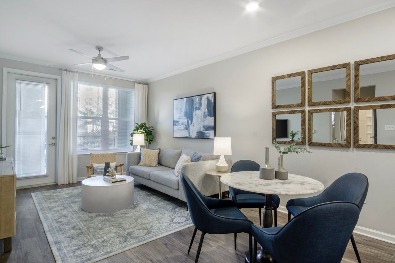 Living room of a modern apartment with a gray sofa, round marble dining table, and wall art at Atlantic on the Avenue in North Charleston, SC.