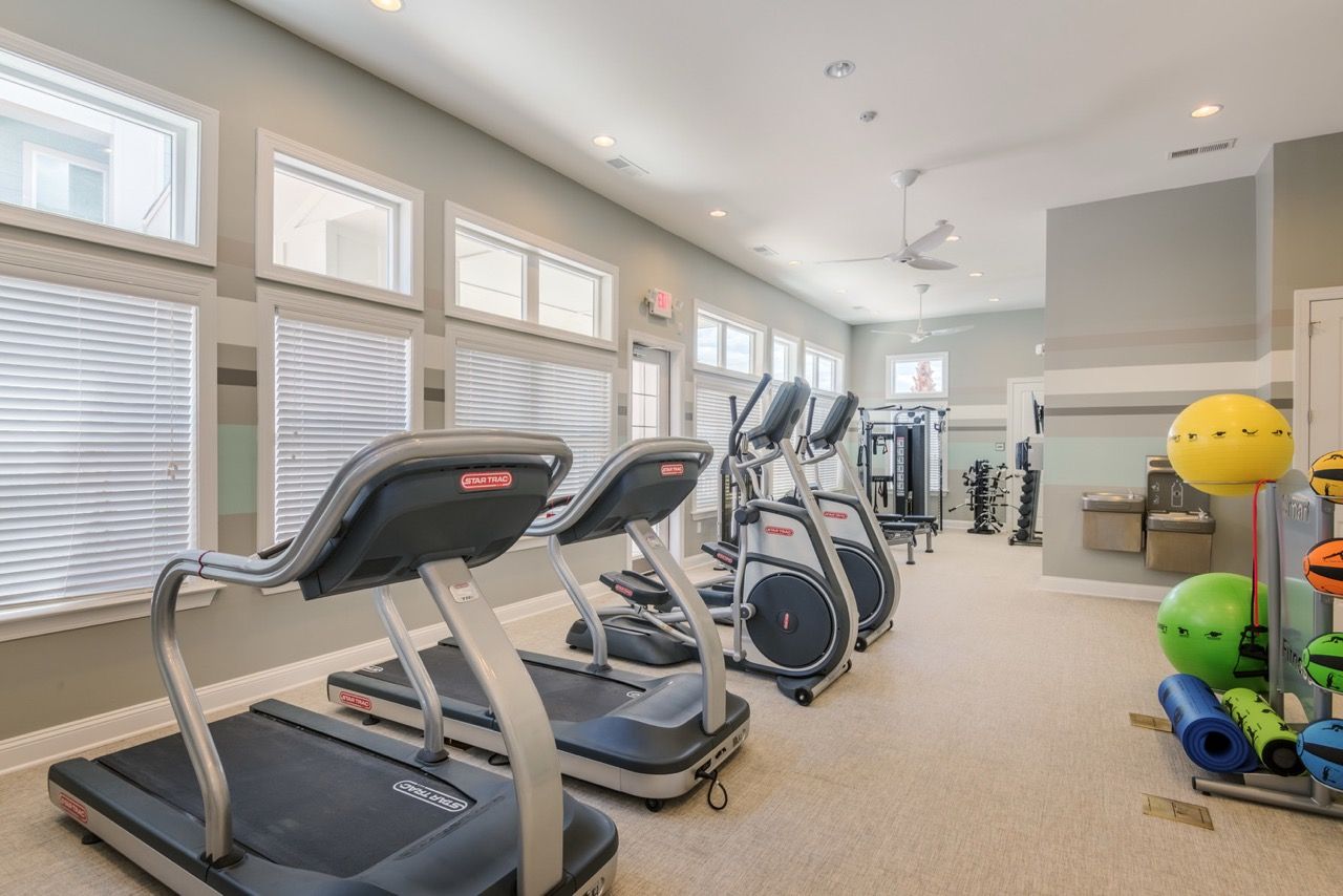 Bright apartment community gym with treadmills, ellipticals, weights, and bright windows at Atlantic on the Avenue in North Charleston, SC.