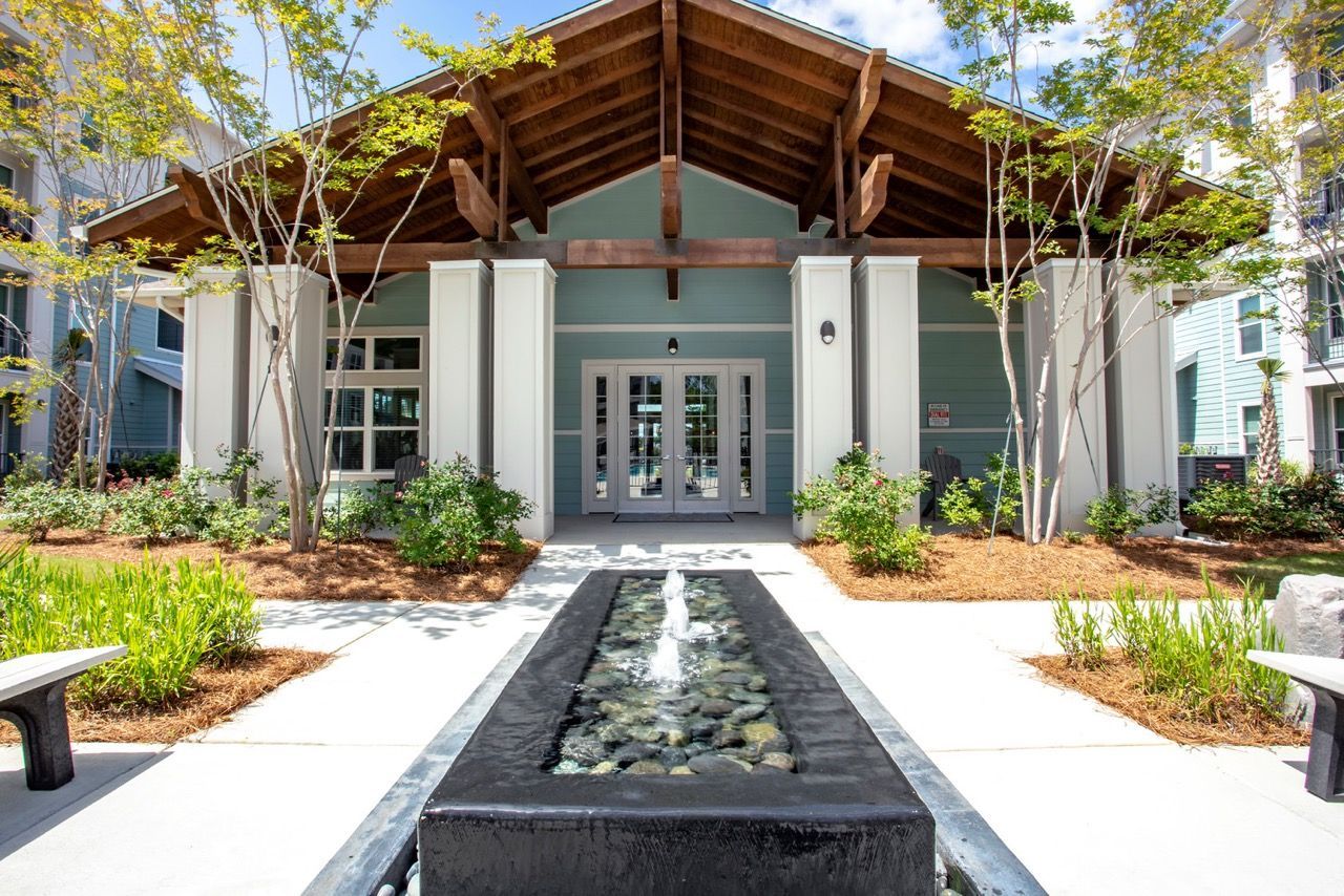 Exterior apartment community entrance with a rectangular water fountain and landscaping at Atlantic on the Avenue in North Charleston, SC.