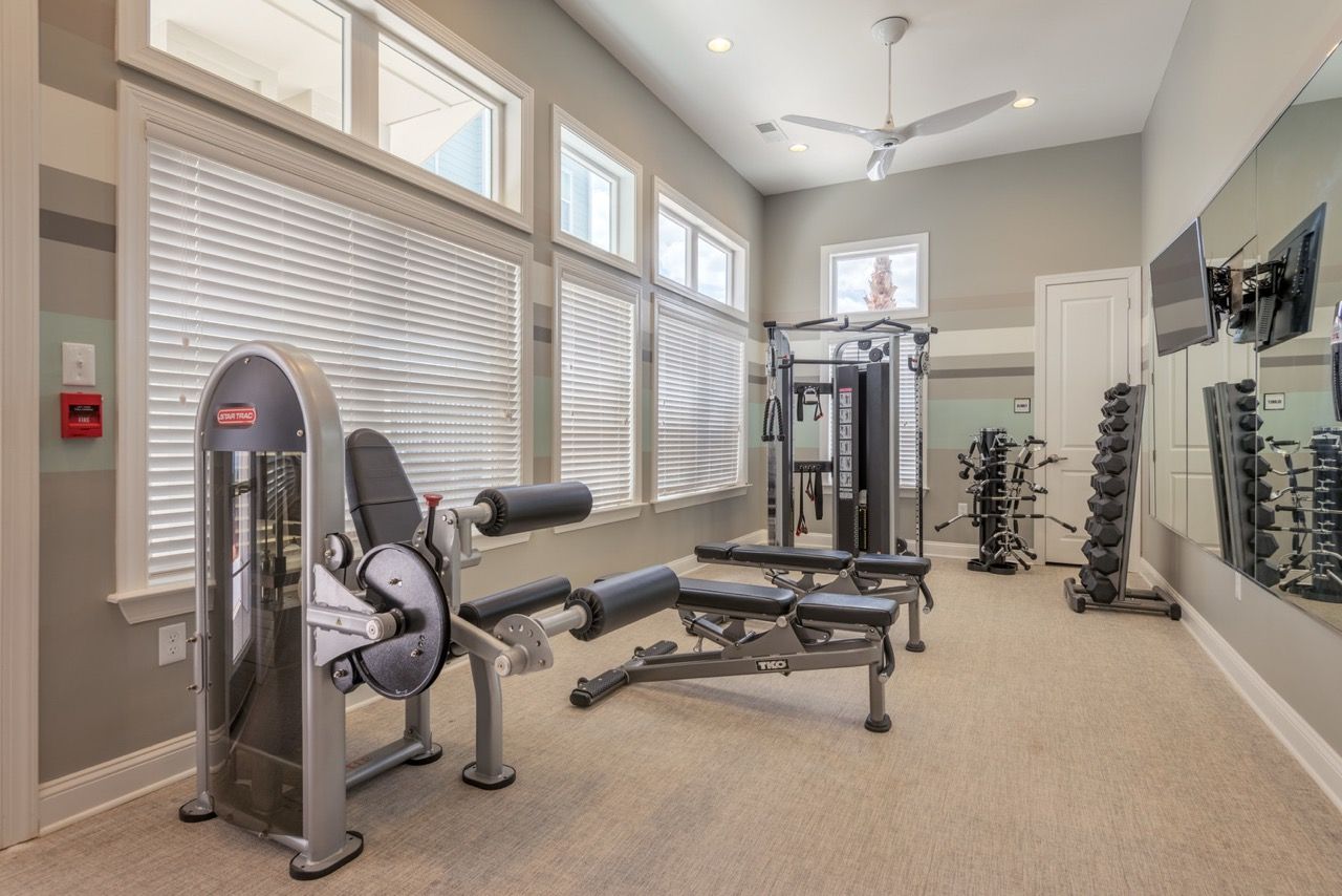 Well-lit community gym with cardio and weight machines, large windows, and mirrors at Atlantic on the Avenue in North Charleston, SC.