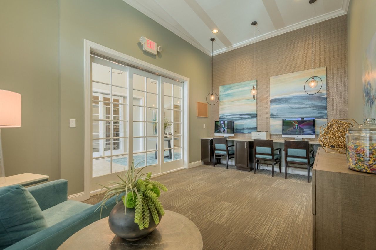 Community lounge with computer workstations, seating, and modern decor at Atlantic on the Avenue in North Charleston, SC.