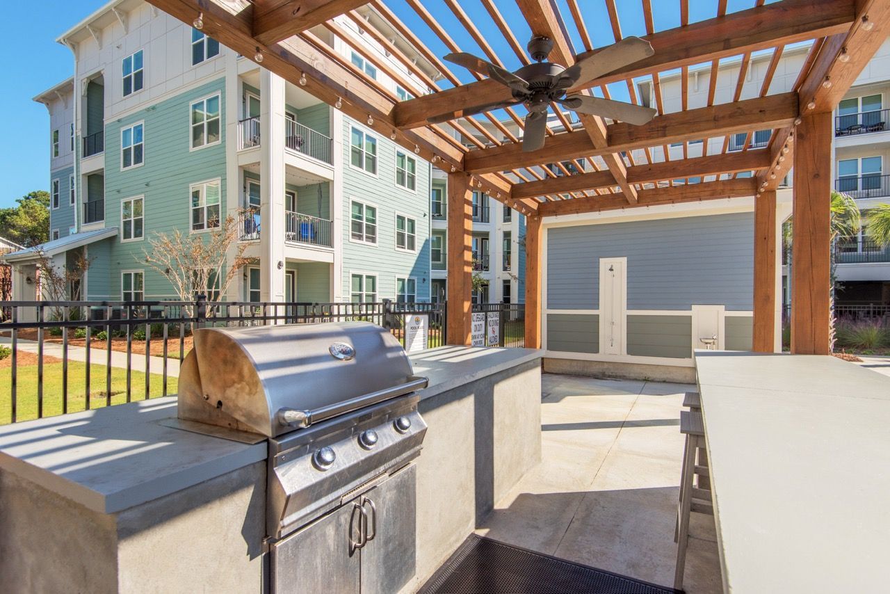 Outdoor community grilling area under a wooden pergola with a built-in grill at Atlantic on the Avenue in North Charleston, SC.