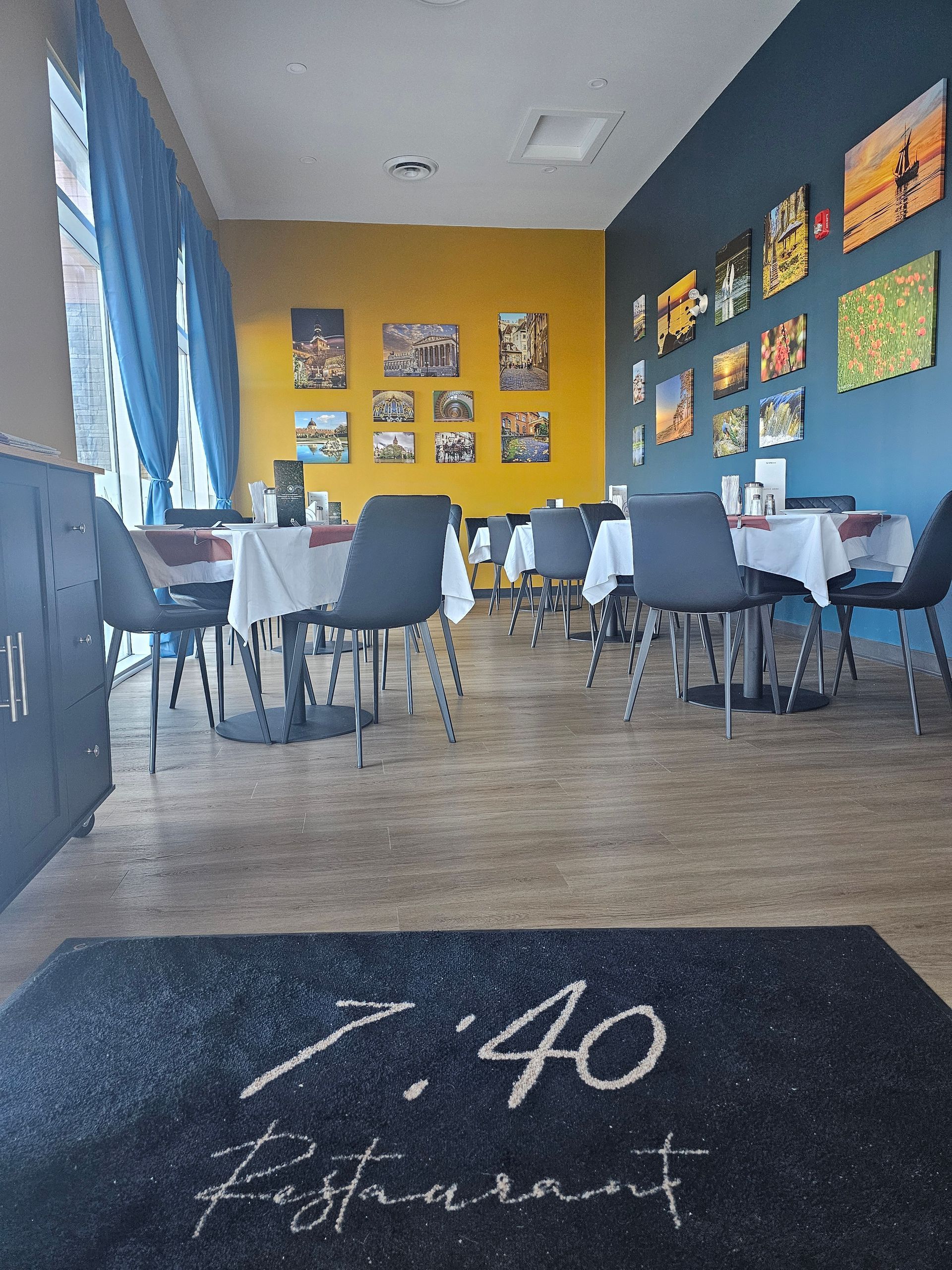 Restaurant interior with tables, chairs, art on the walls, and a welcome mat with 
