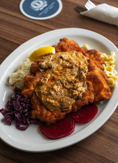 Plate of breaded meat with mushroom gravy, sides include noodles, cabbage, and beets.