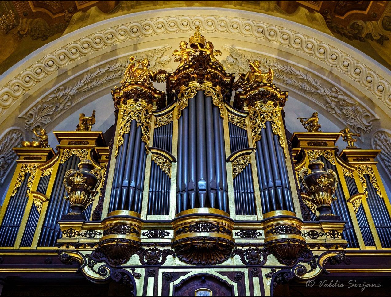 Ornate pipe organ with gold accents in a church setting.