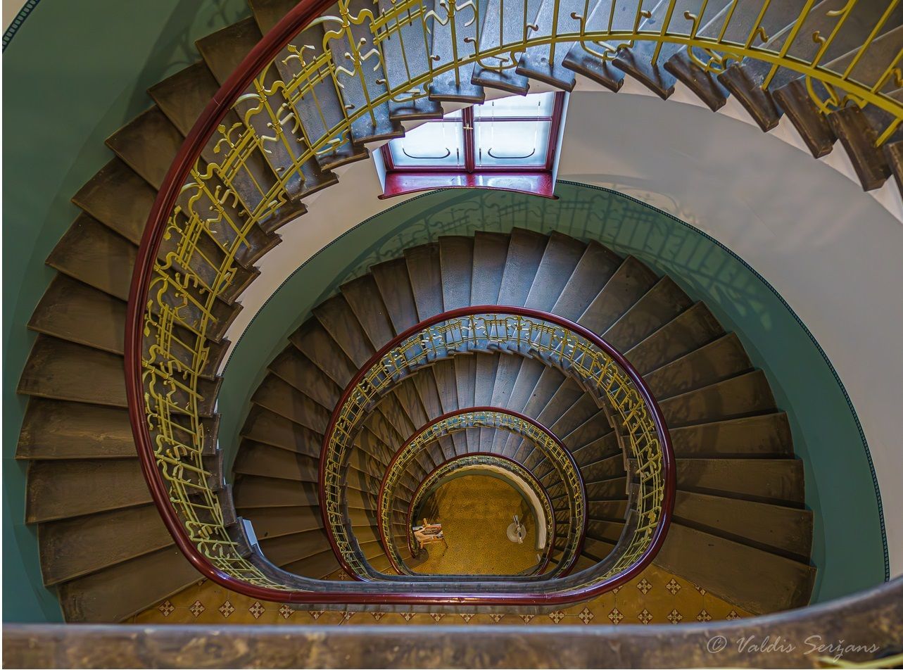 Spiral staircase with wooden steps, yellow railing, and a red-framed light fixture.
