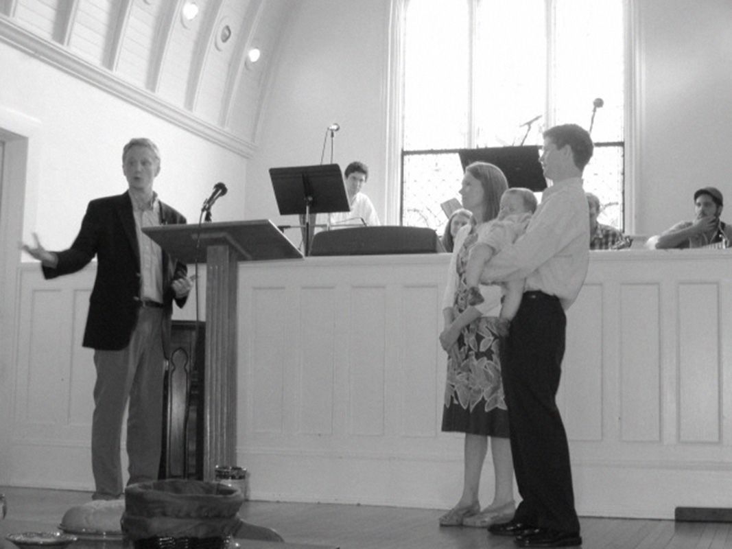 People standing at a church podium during a formal indoor ceremony