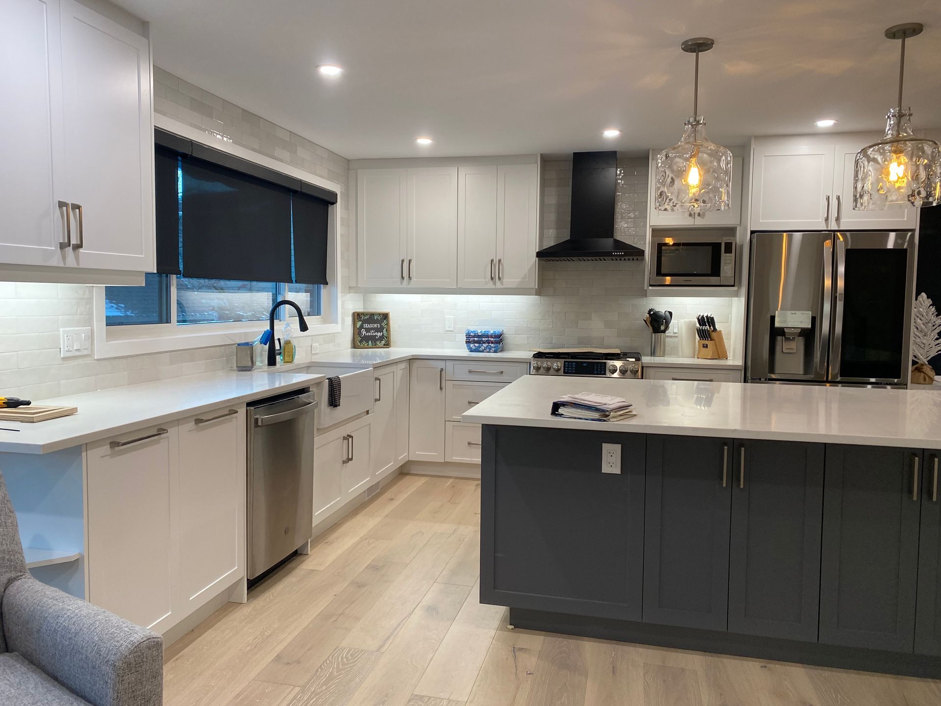 Modern kitchen with white and gray cabinets, stainless steel appliances, and a central island.