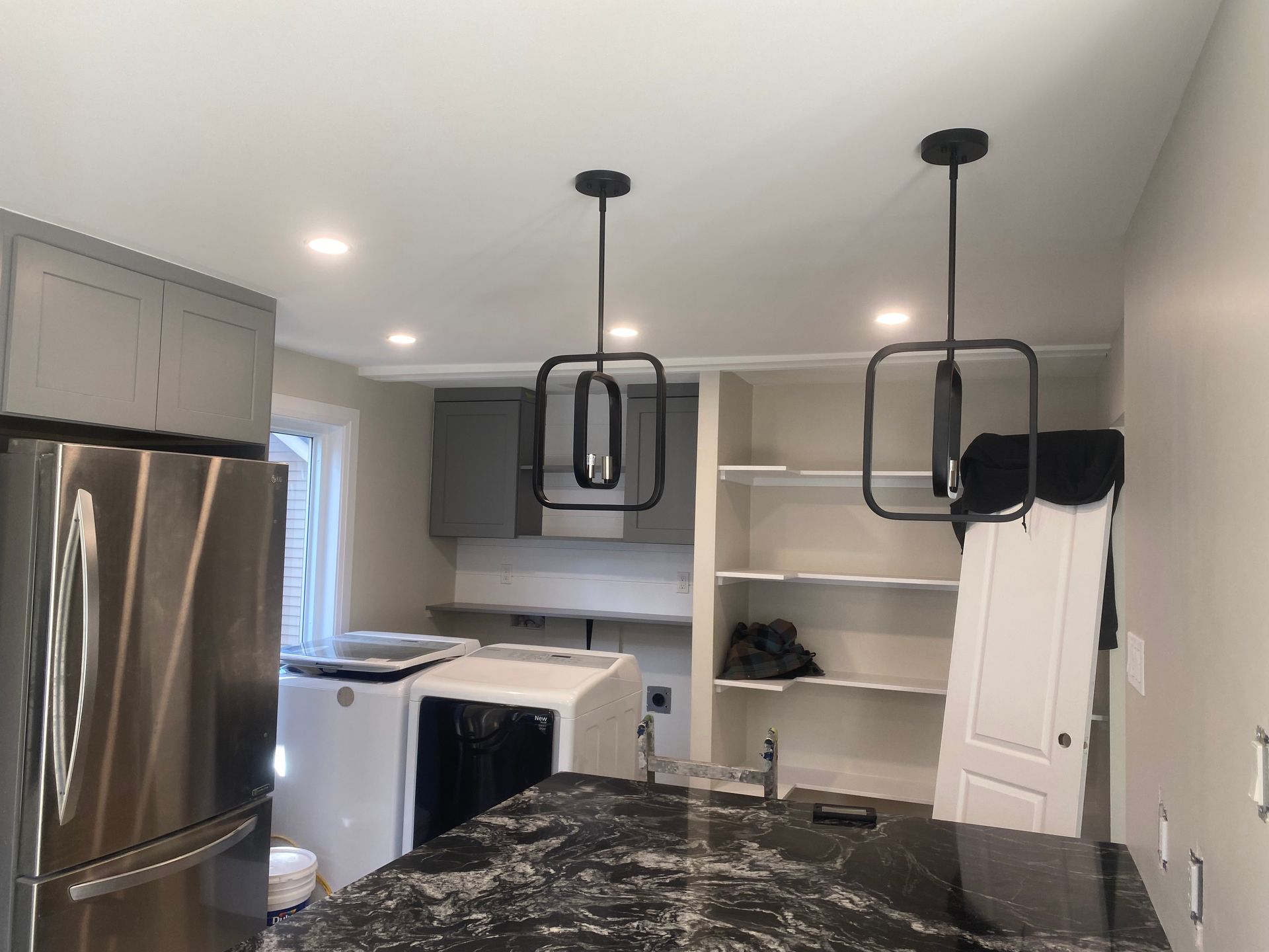 Modern kitchen with black pendant lights, stainless steel appliances, and a granite countertop.