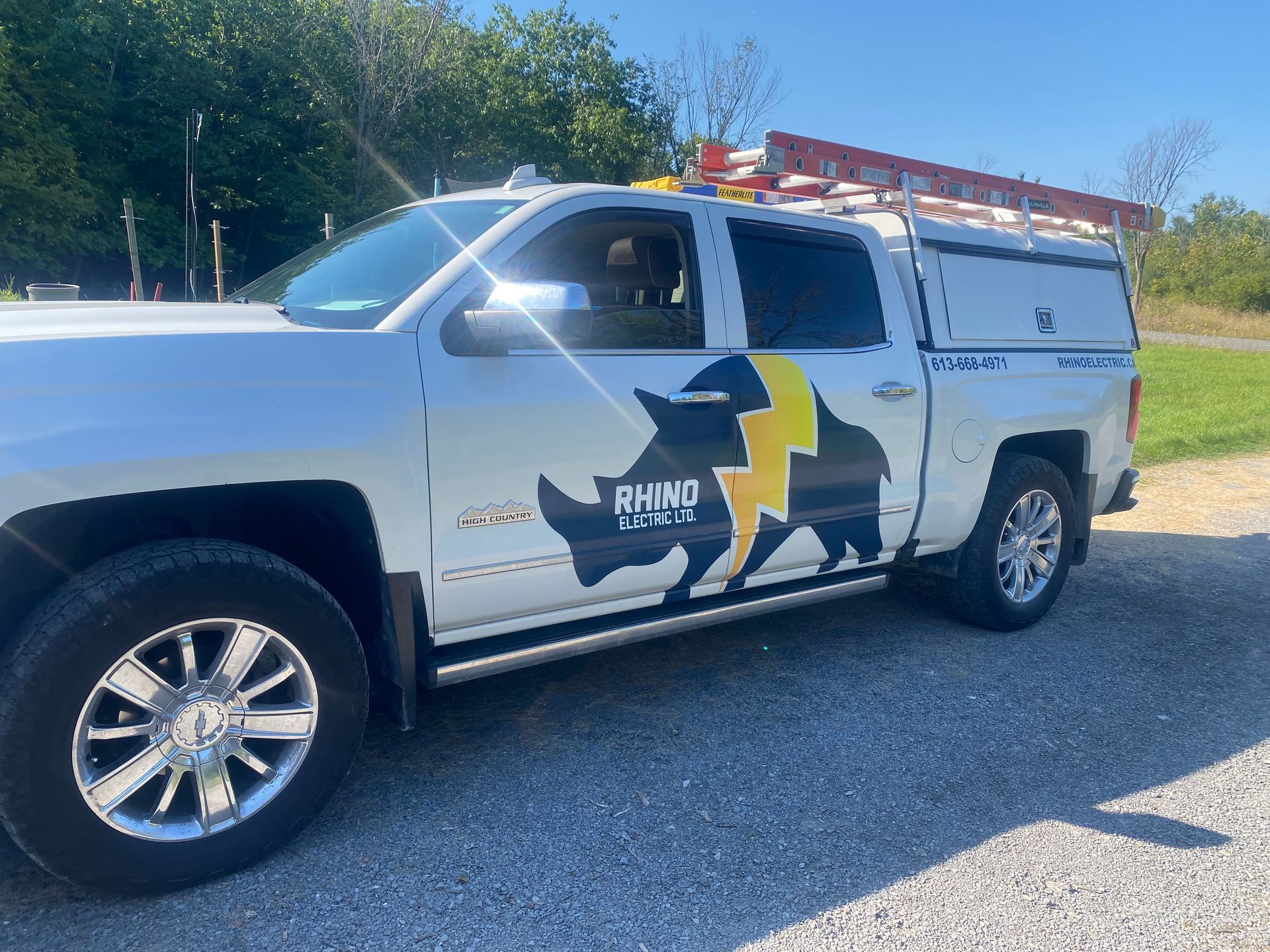 White truck with Rhino Electric logo on the side, parked outdoors on a sunny day.