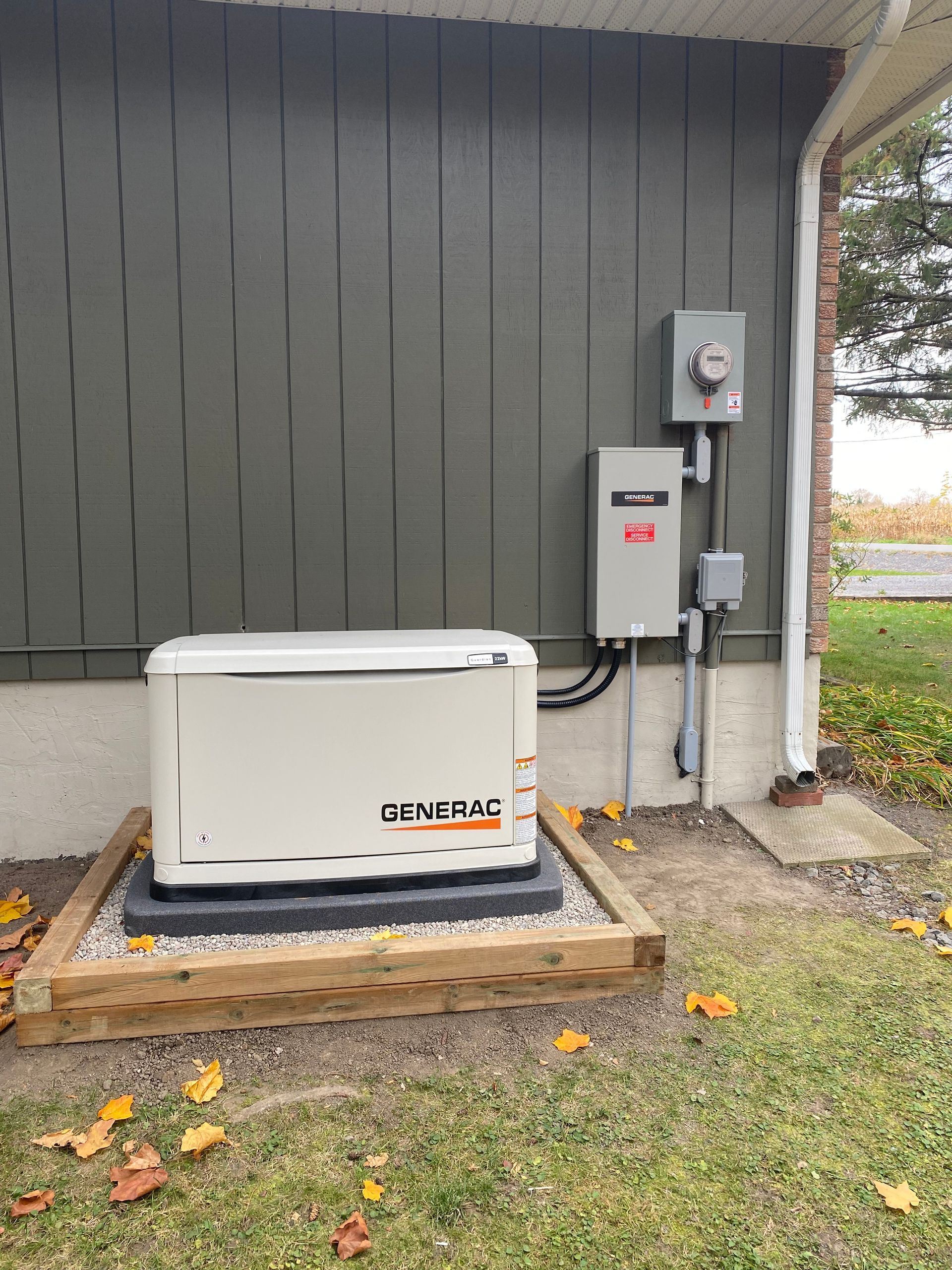 Generac generator unit installed outdoors next to a house with electrical components.