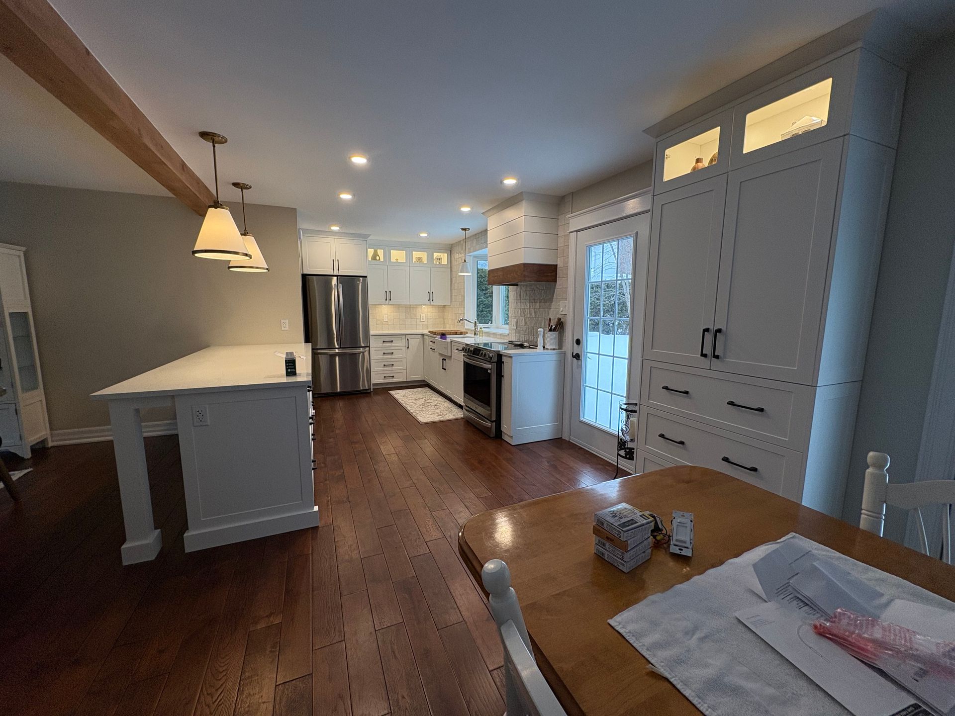 Spacious kitchen with wood floors, island, white cabinets, and stainless steel appliances.
