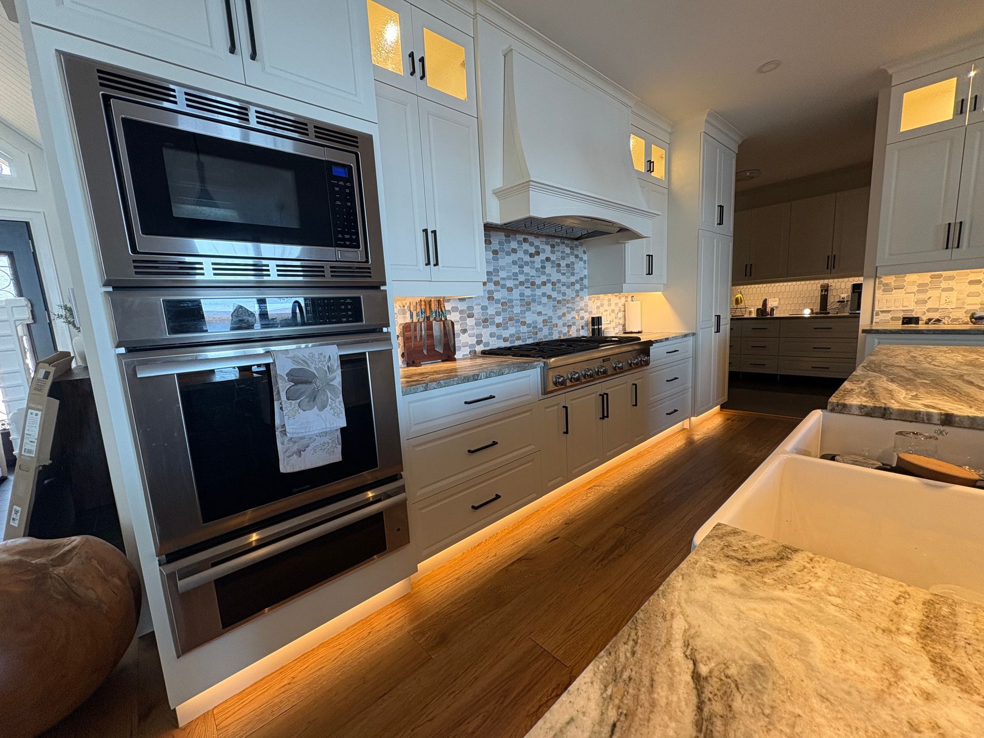 Modern kitchen with white cabinets, stainless steel appliances, and under-cabinet lighting.