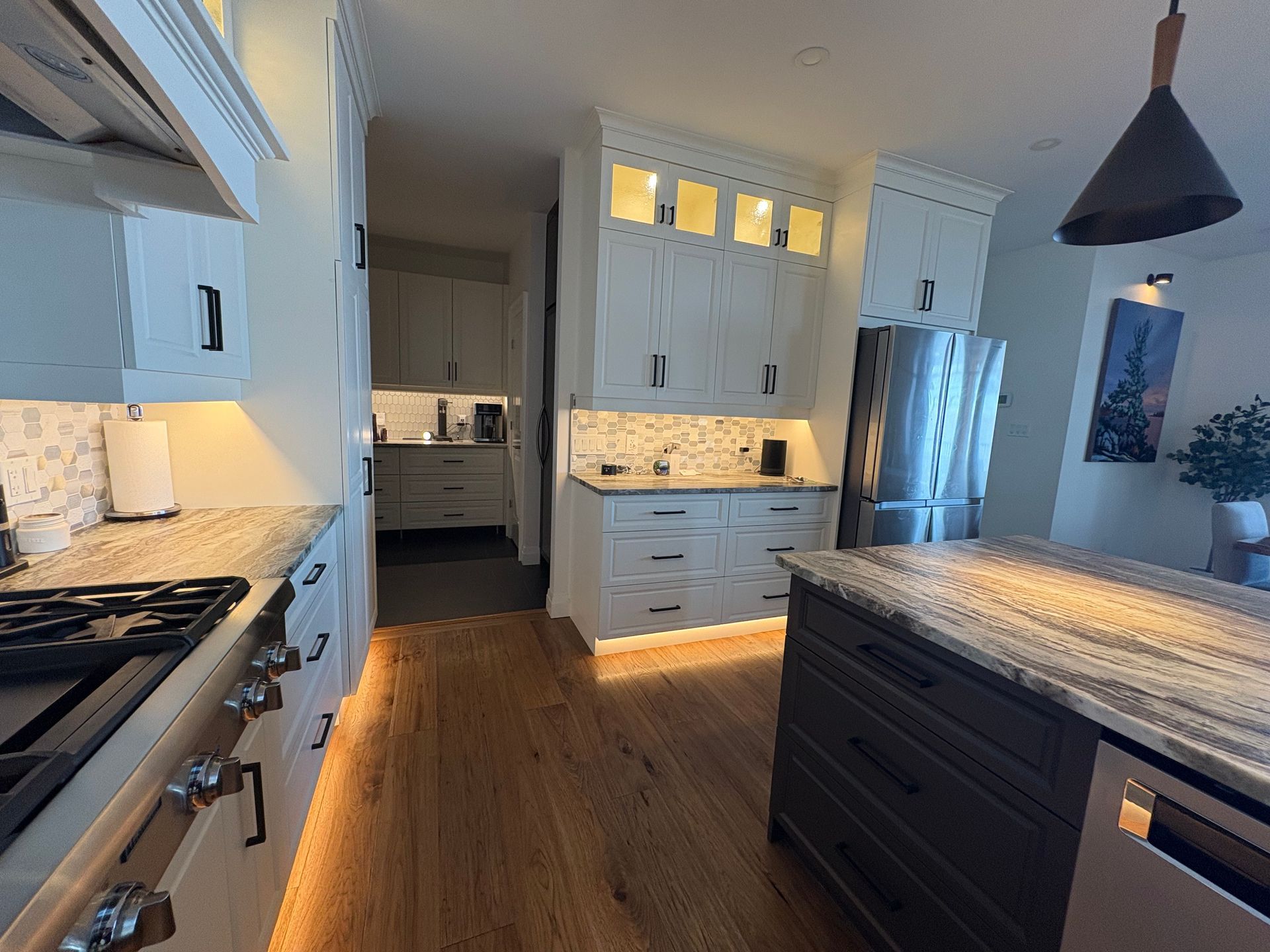 Kitchen with white cabinets, stainless steel appliances, and wood flooring.