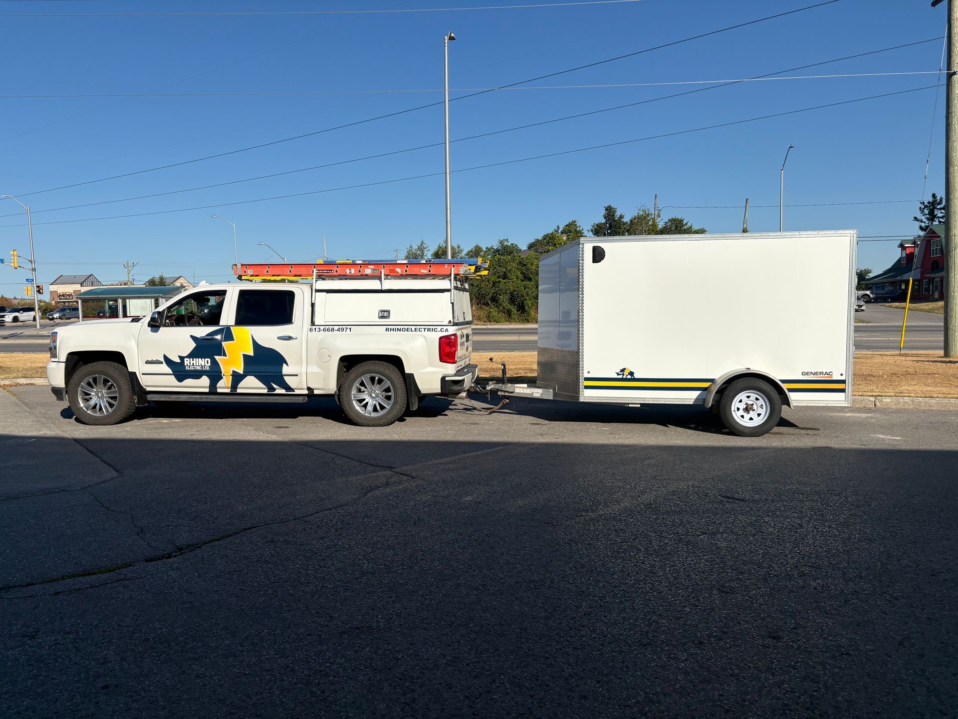 White truck towing a white enclosed trailer parked on asphalt. Clear, sunny day.