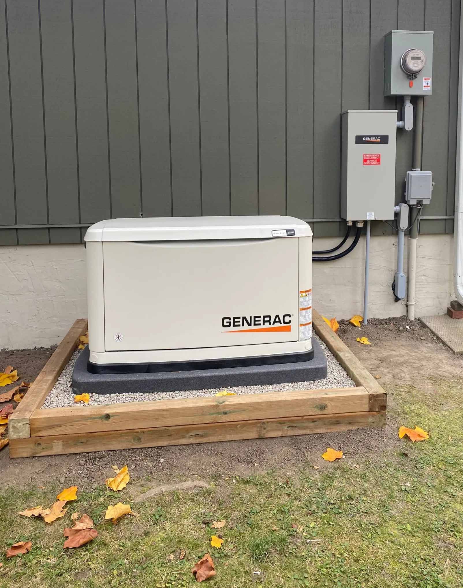 A Generac generator on a gravel base next to a house with electrical components.