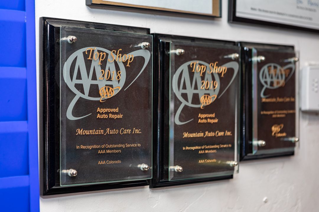 Three framed awards with gold lettering displayed on a wall shelf