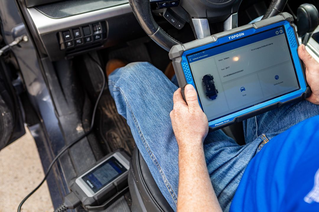 Person in a car using a blue tablet, with feet on the floor and the dashboard visible.