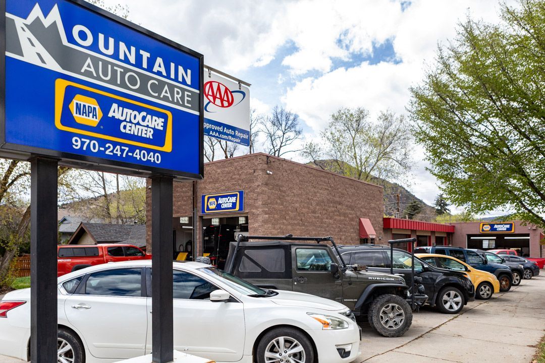 Mountain Auto Care sign beside a row of parked cars outside a roadside auto shop