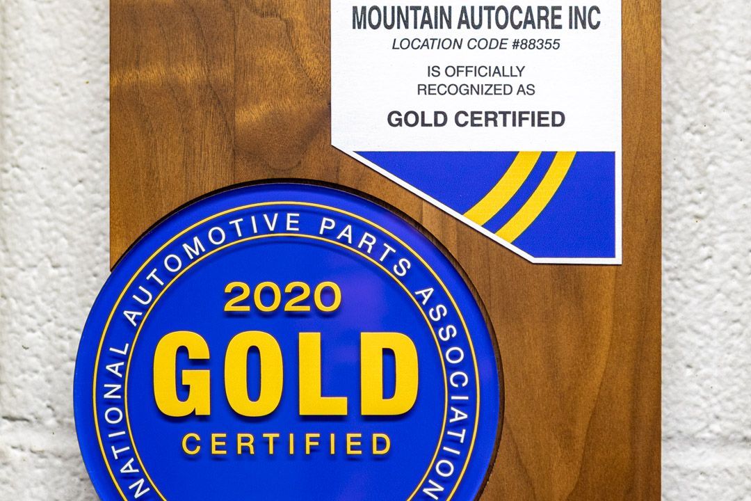 Blue and gold 2020 Gold Certified automotive award plaque on wood wall with Mountain Autocare sign
