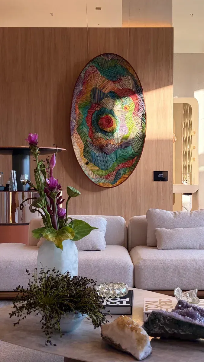 Sala de estar moderna com sofás bege, quadros de madeira, flores e uma mesa de centro.