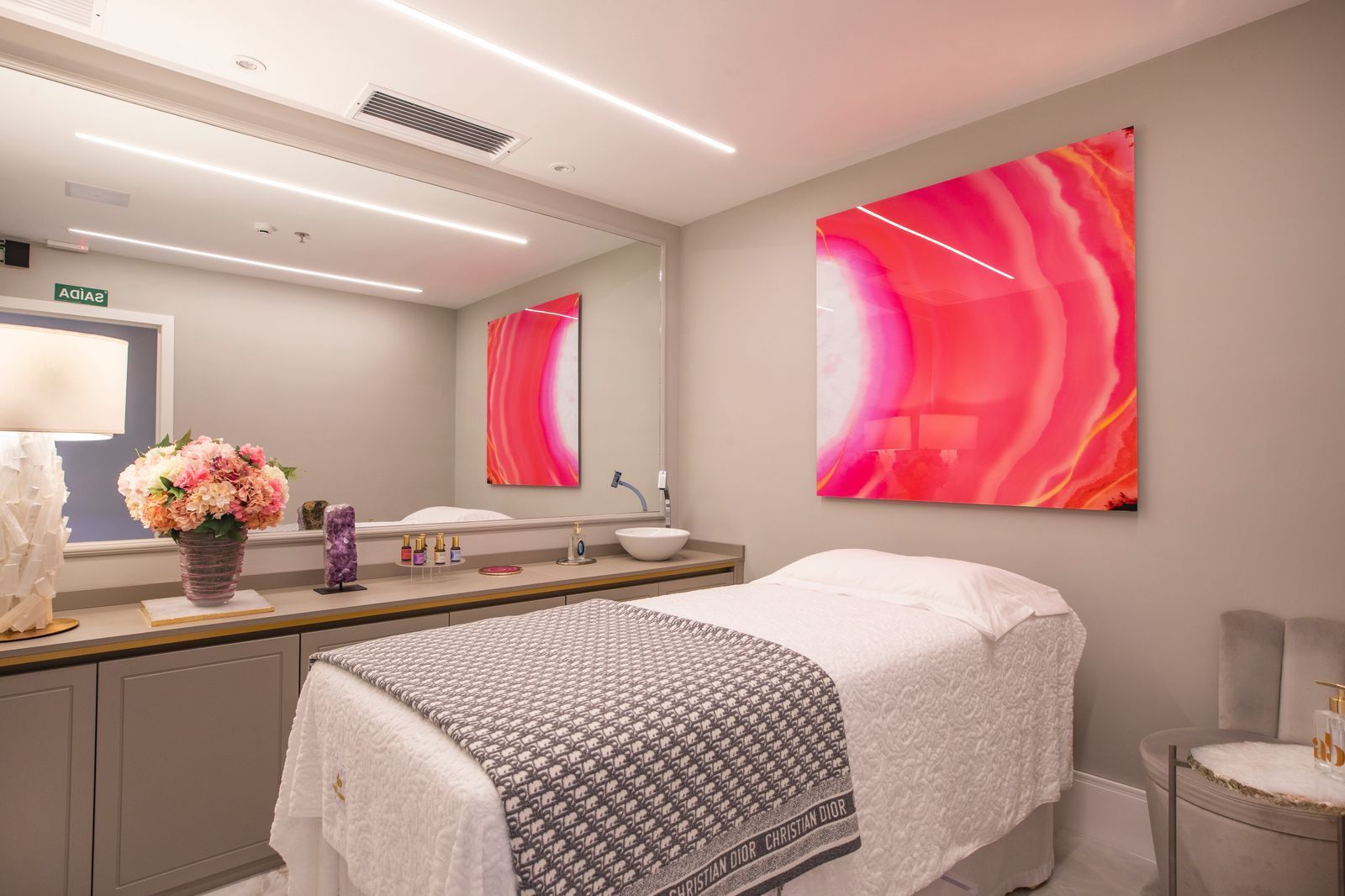 Uma mesa de massagem em uma sala com uma pintura rosa na parede.