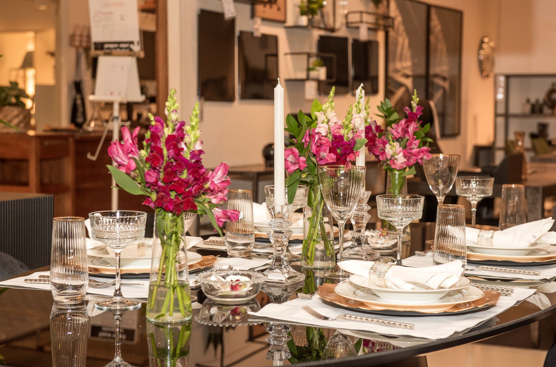 Uma mesa está posta com pratos, copos e vasos de flores.