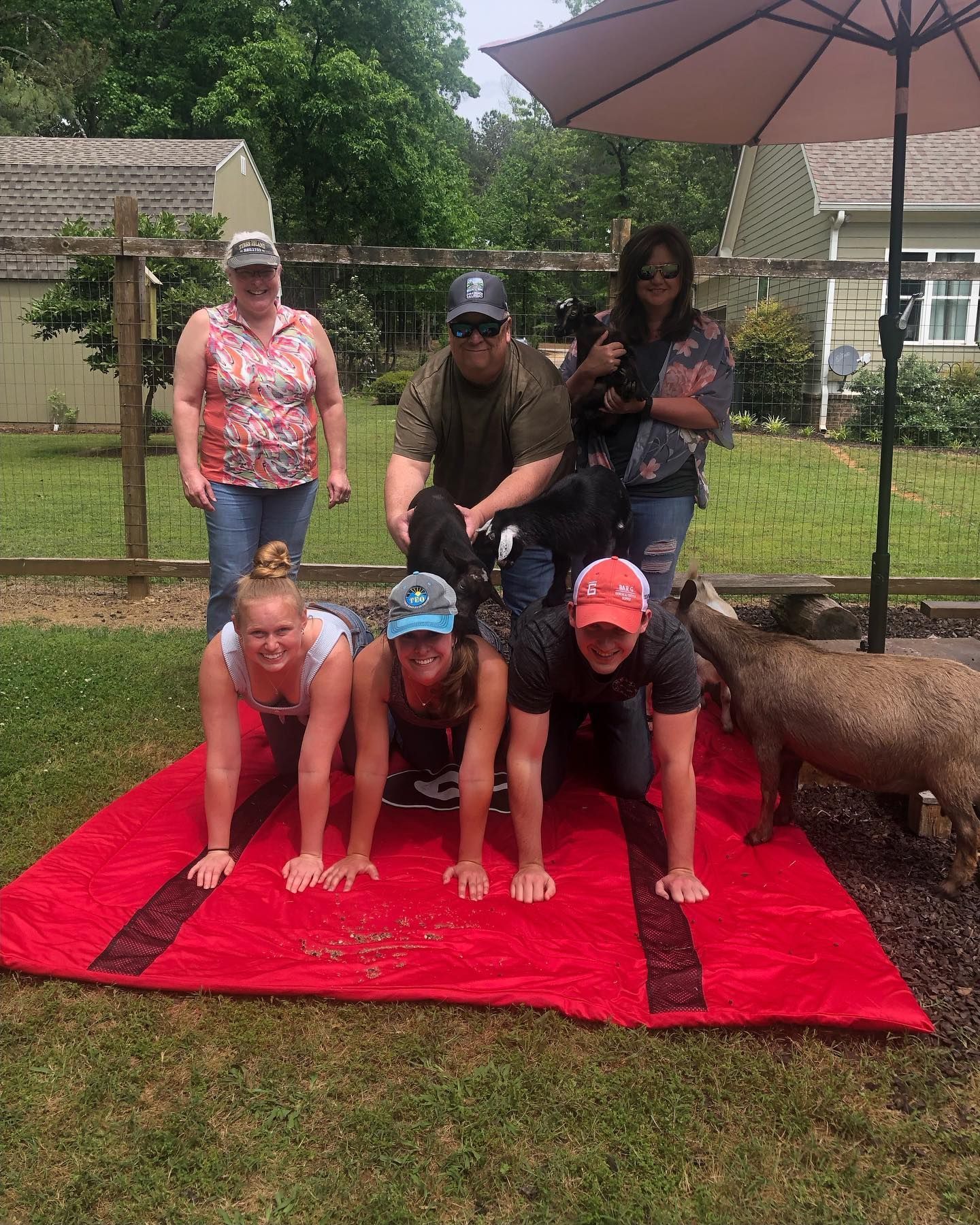 A group of people are doing push ups on a red blanket.