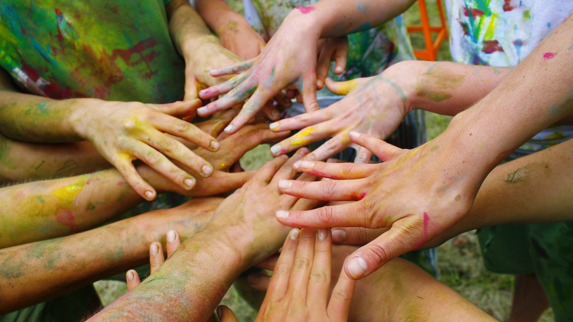Hands covered in paint all reaching into the center.