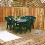 A wooden deck with a table and chairs in front of a wooden fence.