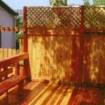 A wooden deck with a wooden fence and a bench.