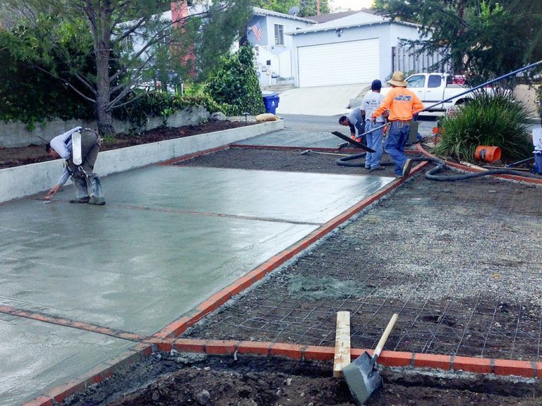 A group of men are working on a concrete driveway